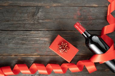 Aziz Sevgililer Günü ayarı, tahta zemin üzerinde kurdele ve kırmızı şarap, düz yatış, üst manzara. Boşluğu kopyala