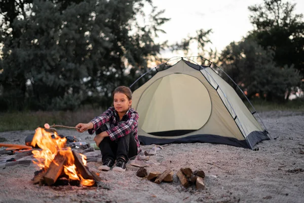 girl roasts marshmallows on a campfire in the evening. Copy space