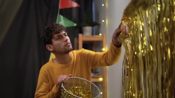 Arabský Muž Úklid Večírku Doma Odstraňuje Zdi Zlatou Fólii Konceptu — Stock video