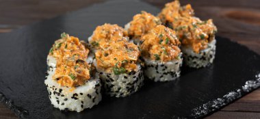 Lezzetli taze suşi, midye, salatalık, somon ve siyah susam tohumlu siyah kayrak taşı. Japon suşi seti. Pankart