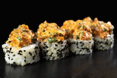 Suşi dürümleri siyah arka planda, yansımalı. Geleneksel Japon yemekleri, bakış açısı. Boşluğu kopyala