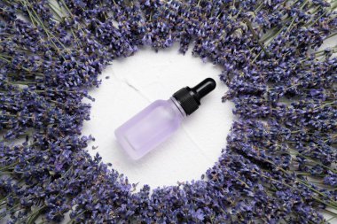 Beyaz beton zemin üzerinde lavanta çiçekleri ve doğal kozmetik içeren düz bir bileşim vardı. Boşluğu kopyala