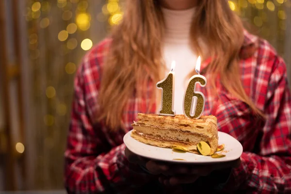 年轻女人拿着盘子和美味的生日蛋糕 上面点着16个数字的蜡烛 挡住分散的灯光 复制空间 — 图库照片
