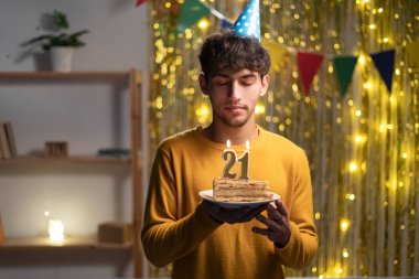 21. yaş gününü evde kutlayan adam, elinde mumlarla pasta tutuyor ve dilek tutuyor, boşluğu kopyalıyor.