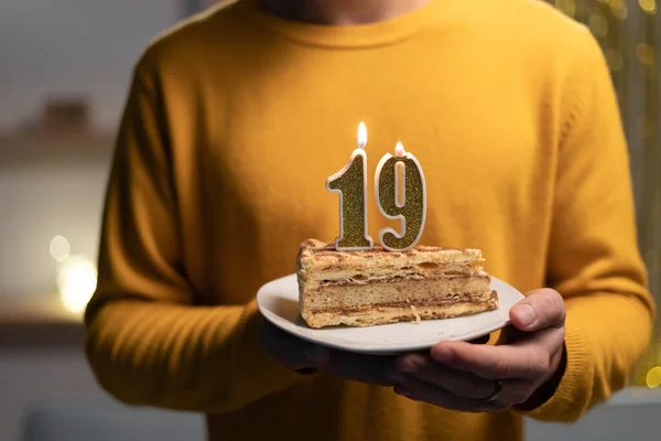 Cake with the number 19 lighted candles in men hands. 19th birthday concept