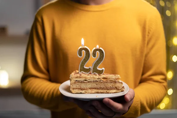 Cake with the number 22 lighted candles in men hands. 22th birthday concept