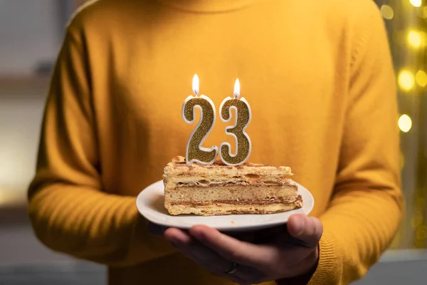 Cake with the number 23 lighted candles in men hands. 23th birthday concept