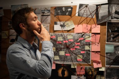 Dedektif ofisinde kanıt panosuna bakıyor ve sigara içiyor. Boşluğu kopyala