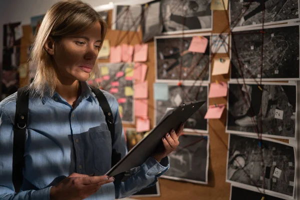 Detective looking at evidence board in her office. Copy space