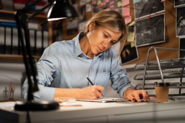 Dedektif ofisinde masasında çalışıyor. Boşluğu kopyala