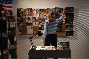 Woman detective searching terrorist act connections looking at investigation board. Copy space