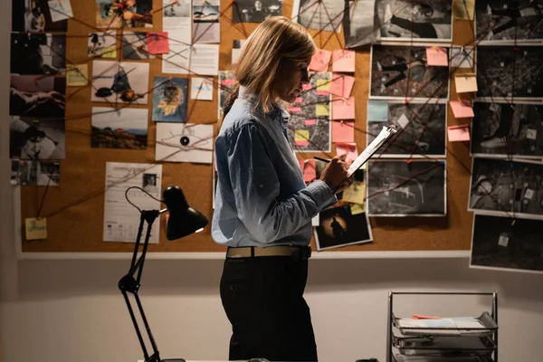 Serious female detective working in her office with evidence, copy space