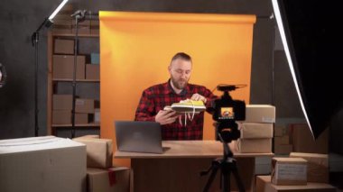 Genç bir işletme sahibi, bir internet mağazası için ev videosu stüdyosunda mal değerlendirmesi yapıyor. Kamera sarı spor ayakkabıları gösteriyor. Online giyim mağazası. İş dünyası sosyal medya etkileyiciName.