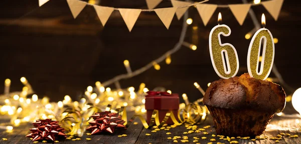 Number 60 golden festive burning candles in a cake, wooden holiday background. sixty years of birth. the concept of celebrating a birthday, anniversary, holiday. Banner. copy space