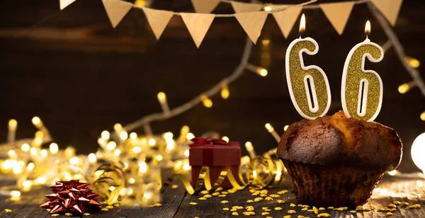 Number 66 golden festive burning candles in cake, wooden holiday background. sixty-six years of birth. the concept of celebrating a birthday, anniversary, holiday. Banner. copy space