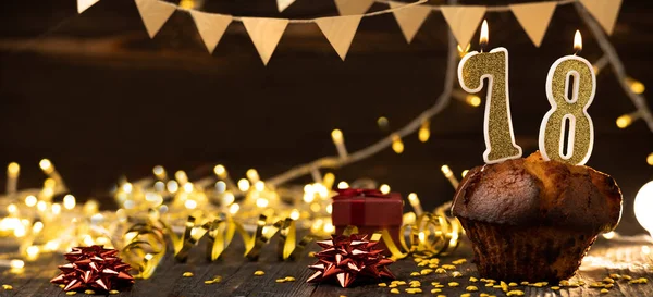 Number 78 golden festive burning candles in a cake, wooden holiday background. seventy-eight years since the birth. the concept of celebrating a birthday, anniversary, holiday. Banner. copy space