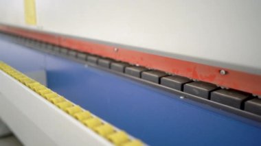 A fragment of a machine with an electric motor for the production of furniture and parts from chipboard. Close-up of laminating machine parts
