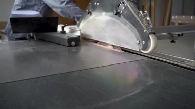 close-up hands of carpenters working with a sliding panel saw and sawing wood fiber board in a furniture factory or chipboard workshop. the concept of production, fabrication and woodworking industry