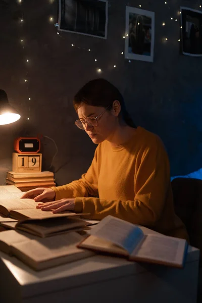 Girl college student studying in dormitory reading books at late night. Copy space
