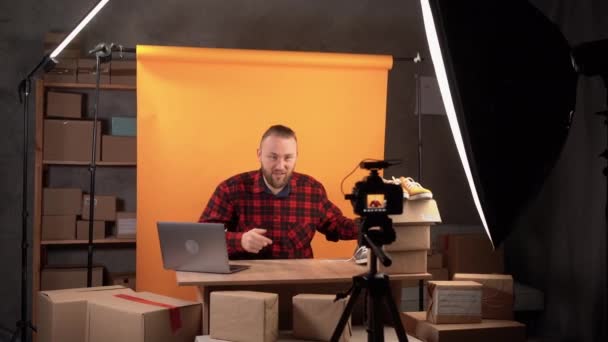 ソーシャルカメラでオンラインで製品を閲覧する白人男性ブロガー 製品を販売するための技術 幸せな笑顔の顔を持つカメラからオンラインストリームを通じて 新しい通常のビジネス — ストック動画