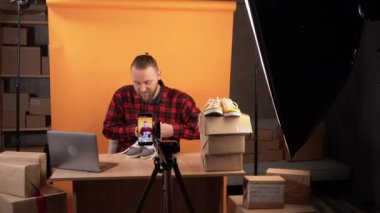bearded caucasian man live streaming clothing review in home studio. testing sports shoes for durability. sales online. Working as a video blogger Lookbook.