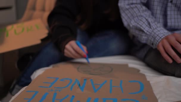 两名学生积极分子在寝室里准备海报 用蓝色标识写一张海报 阻止气候变化 男人和女人都在为抗议做准备 — 图库视频影像