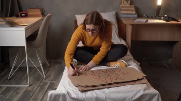 女子大生の寮の活動家が夜にベッドに座って赤いマーカーでポスターを書いてる 抗議行動の準備の概念 コピースペース — ストック動画