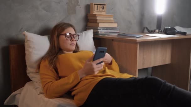Close Smiling Student Teenager Lying College Dorm Holding Smartphone Bank — Stock video
