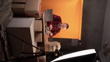Powerful bearded caucasian man live streaming sportswear review in home studio. Recording on camera. Sell shoes online. Working as a video blogger Show of clothes. Lookbook. Vertical video