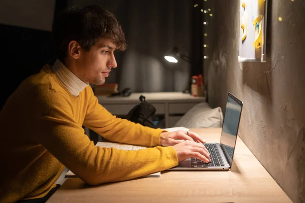 Arabic university student in dorm working on laptop at night. Copy space