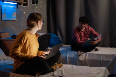 Students preparing for exams and doing homework in student hostel dormitory at night. Copy space