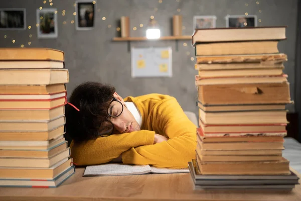 Student studying hard exam and sleeping between books in library. Copy space