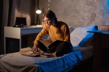 Smart female student prepare for exam in dormitory room at night. Copy space
