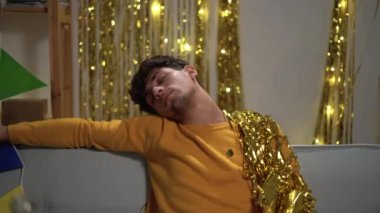 After great party. Exhausted, tired, drunk guy is sleeping after night birthday event on the sofa in living room, having a lot of litter, rubbish around them