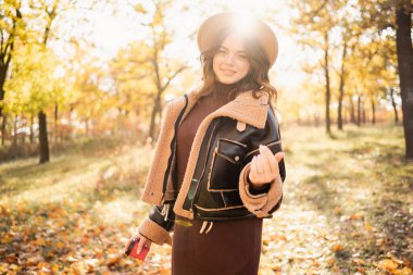 Happy beautiful woman in forest in fall colors, celebrating coming autumn. Copy space