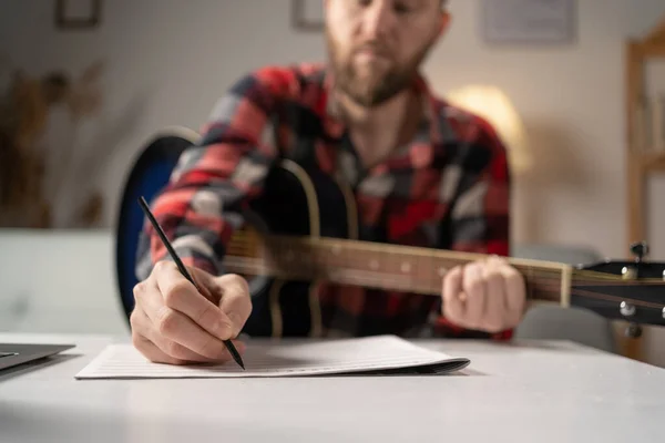 Man musician writing song with guitar at home, close up. Copy space