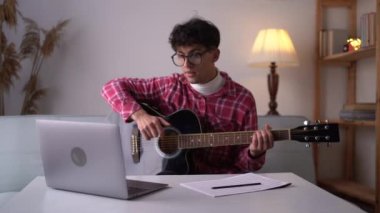 young man learning to play guitar at home, hobby concept. Copy space