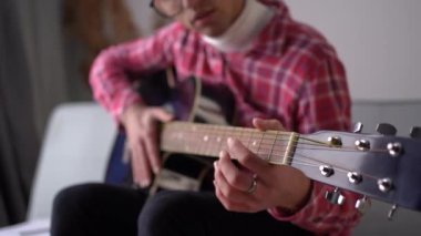 Arab guy with acoustic instrumental guitar playing new written song sound signing creative talented person in living room indoors. Copy space