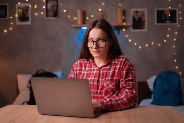 Portrait of young casual student working or studying using laptop computer at home office or in the student dormitory. Indoors image. Copy space