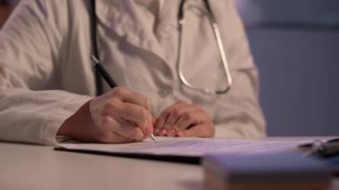 Woman Doctor working and taking note information of patient in checklist paper on clipboard in medical room of hospital at night. Health care concept. Copy space