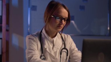 Female doctor working with laptop at night in clinic at his working place. Young physician at work. Medical service, medicine concept