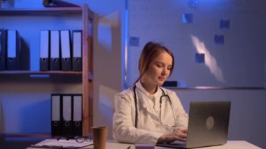 Female doctor use laptop computer at night in clinic office. Copy space