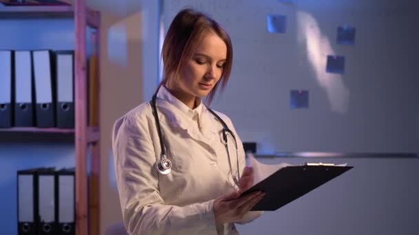 Quality Medical Services Female Doctor Uniform Reading Notes Clipboard While — Stockvideo