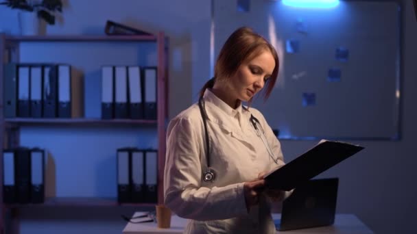 Γυναίκα Γιατρός Λευκό Παλτό Πρόχειρο Ανάγνωση Ιατρική Έκθεση Σκούρο Φόντο — Αρχείο Βίντεο