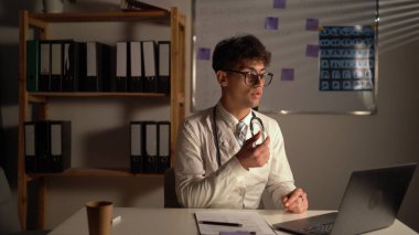 Steteskoplu genç bir doktor, hastanedeki ya da klinikteki bir hastayla bilgisayarla video konferans görüşmesi yapıyor. Teletıp kavramı