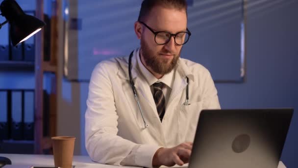 Arzt Mit Brille Tippt Laptop Sitzt Nachts Schreibtisch Dunklen Krankenhauszimmer — Stockvideo