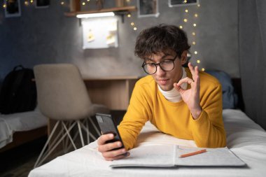Öğrenci video aracılığıyla iletişim kuruyor. Gece yatakta yatarken parmaklarını işaret ediyor. Boşluğu kopyala
