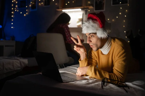 Student celebrating christmas in dormitory at night talking with friend using webcam on laptop computer. Copy space