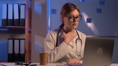 Kadın doktor bilgisayarında boğaz rahatsızlığı olan bir hastaya çevrimiçi video görüşmesi yapıyor. Tıbbi asistan ya da terapist geceleri web kamerasına video konferans veriyor. Teletıp kavramı.