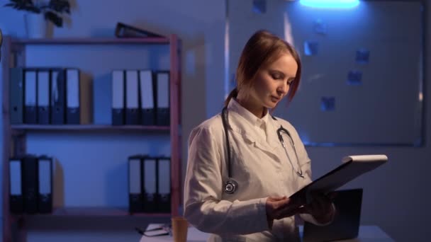Γυναίκα Γιατρός Νυχτερινή Υπηρεσία Λευκό Παλτό Διαβάζοντας Τους Ασθενείς Πληροφορίες — Αρχείο Βίντεο